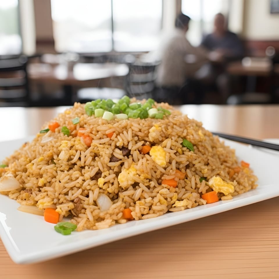 A large plate of Stix By AZN fried rice with vegetables and egg, topped with green onions.